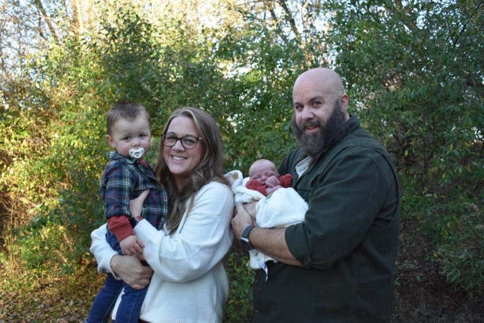 Joel Rightler with his wife and two young children, outdoors in autumn